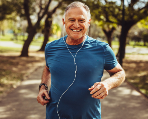 A man running in the park wearing headphones.