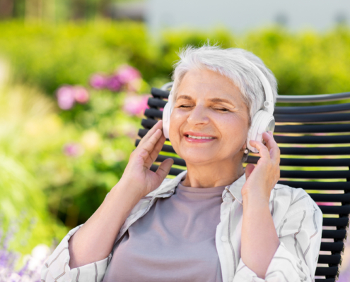 A woman sitting on top of a bench wearing headphones.