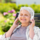 A woman sitting on top of a bench wearing headphones.